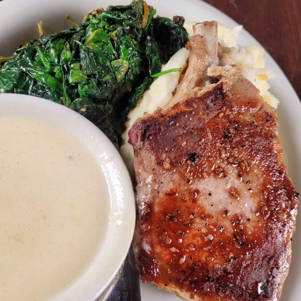 River Grille's pork chop with mashed potatoes, cream sauce, and sauteed spinach.