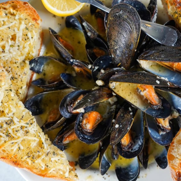 Steamed mussels in a buttery sauce with garlic bread and a lemon wedge at River Grille.
