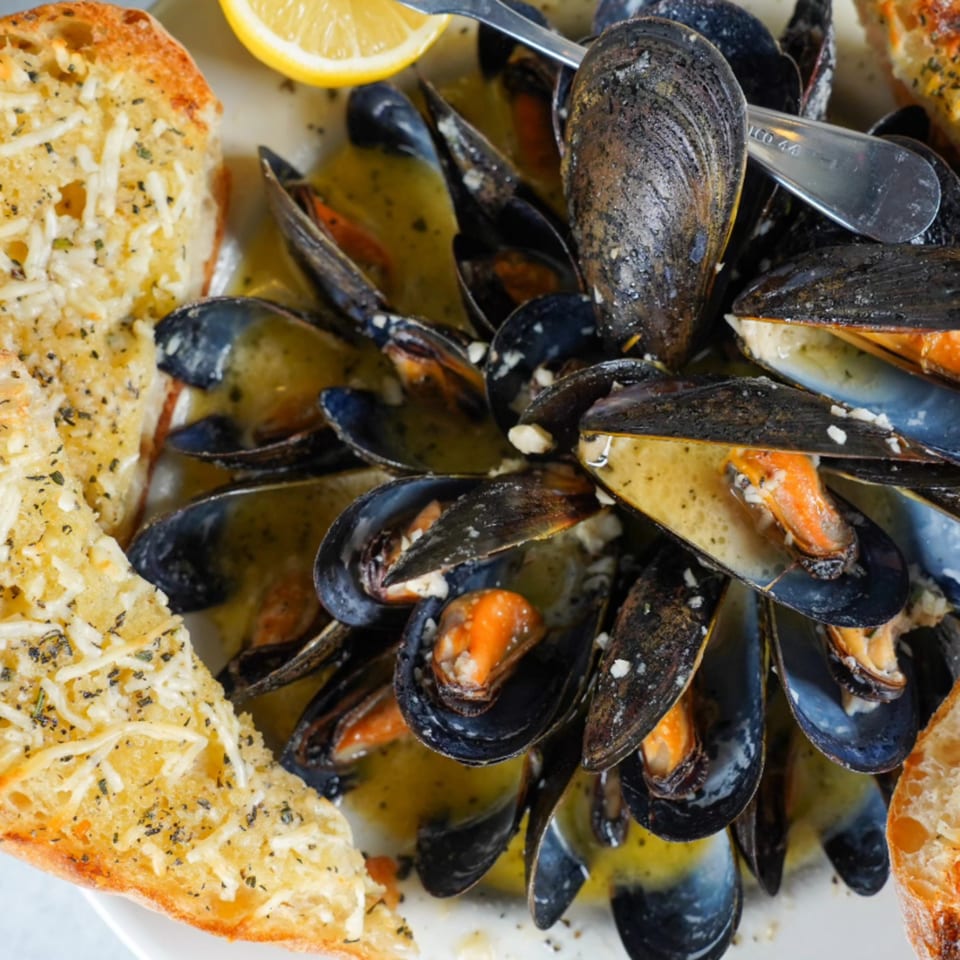 Steamed mussels in a buttery sauce with garlic bread and a lemon wedge at River Grille.